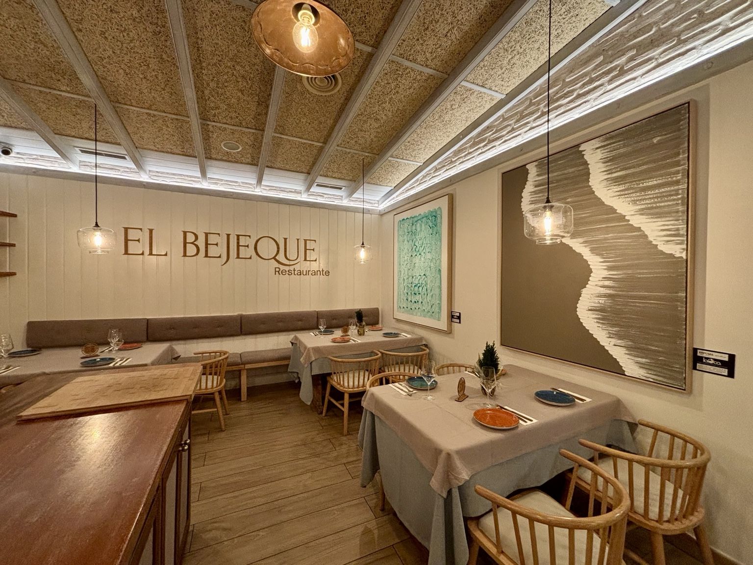 Sala de El Bejeque con mesas vestidas, lámparas colgantes y el rótulo del restaurante