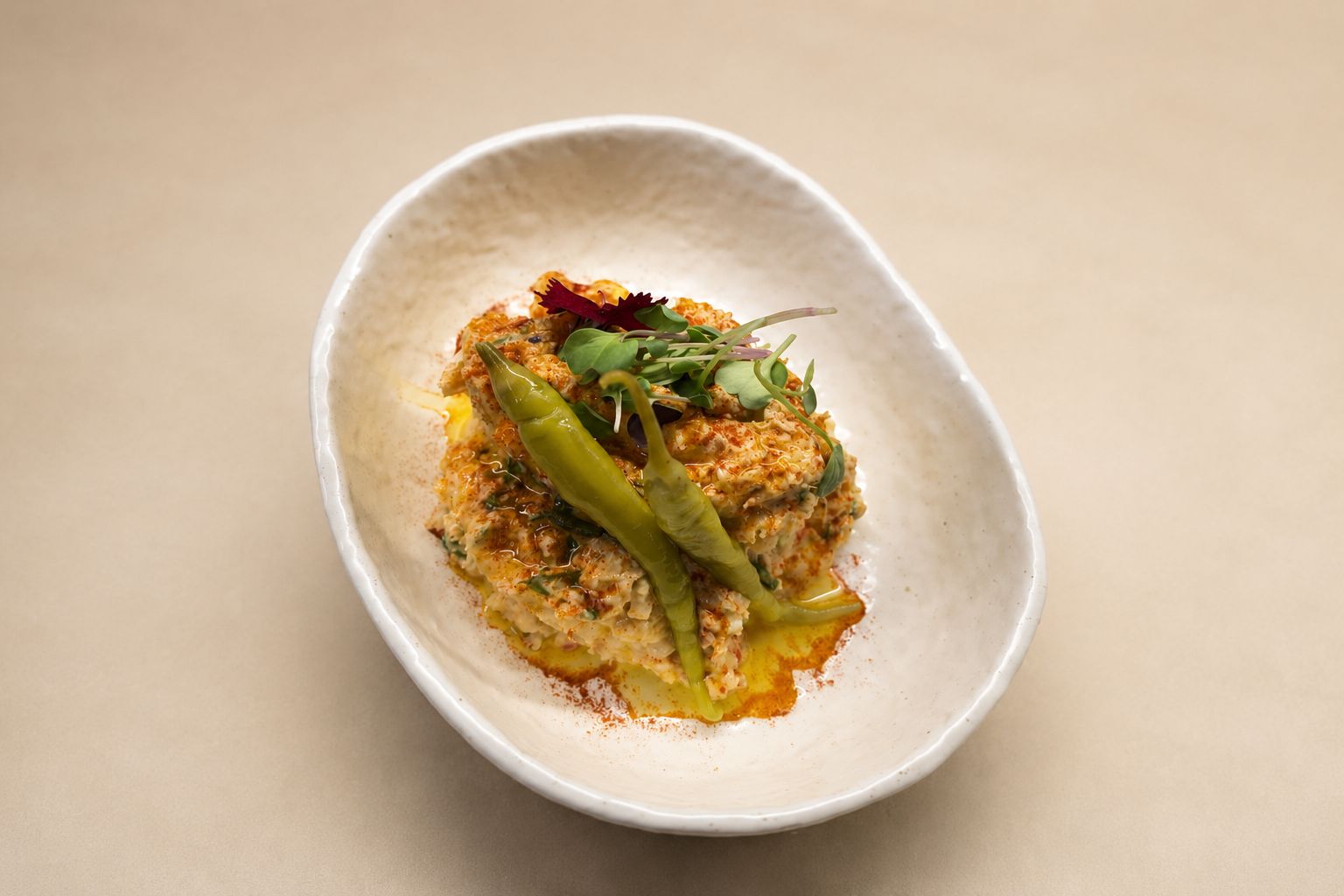 Ensaladilla de batata con piparras, pimentón de La Vera y aceite de oliva virgen extra en cuenco de cerámica